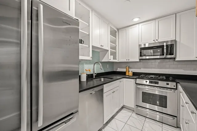 a kitchen with stainless steel appliances granite countertop a stove a refrigerator and a microwave