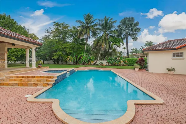 a view of a swimming pool with lawn chairs and plants