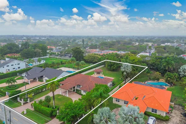 an aerial view of residential houses with outdoor space and trees