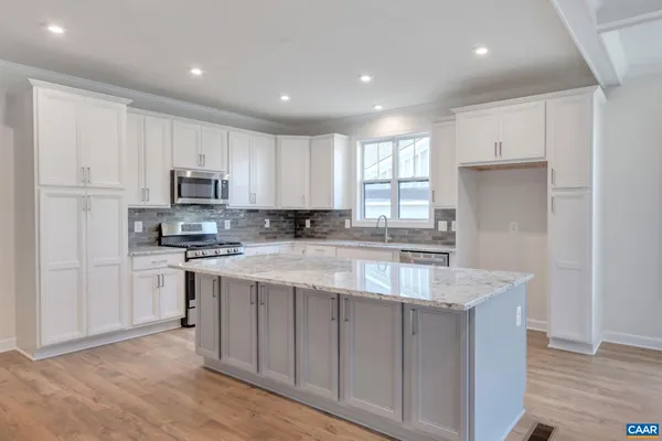 a large kitchen with stainless steel appliances granite countertop a large counter top and a wooden floors