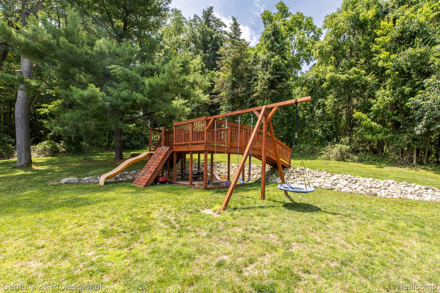 1790 Kent Road Ortonville, MI 48462 - Photo 49 of 64 Expansive green yard featuring a multi-level wooden play structure with a slide, stairs, and swing