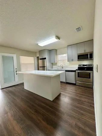 a large kitchen with stainless steel appliances granite countertop a stove a sink dishwasher and a refrigerator with wooden floor