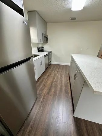 a view of a kitchen with wooden floor and electronic appliances