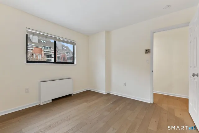 an empty room with wooden floor and window