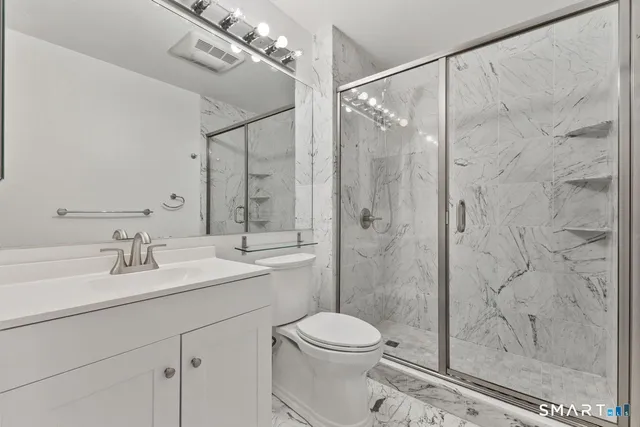 a bathroom with a granite countertop sink a toilet and shower