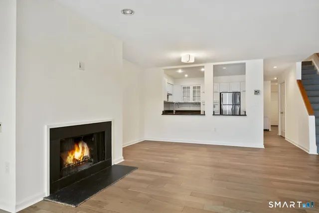 a view of an empty room and kitchen with fireplace