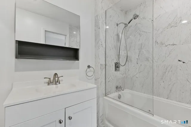 a bathroom with a tub a sink and mirror