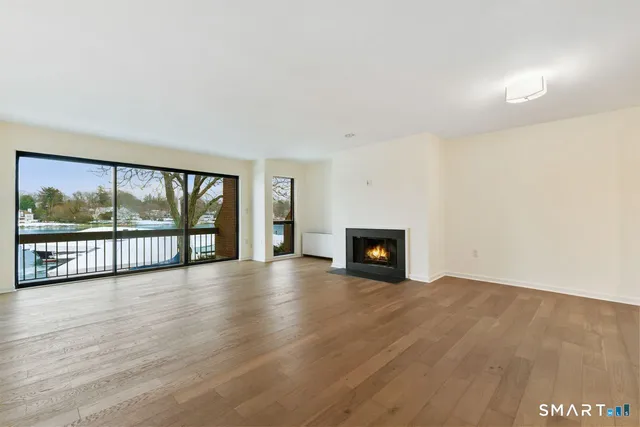 a view of an empty room with wooden floor and a fireplace