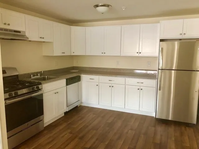 a kitchen with granite countertop white cabinets and white appliances