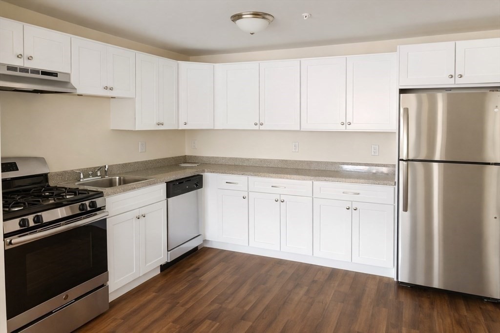 361 Hildreth Street, Unit 24 Lowell, MA 01850 - Photo 2 of 9 a kitchen with cabinets appliances and wooden floor