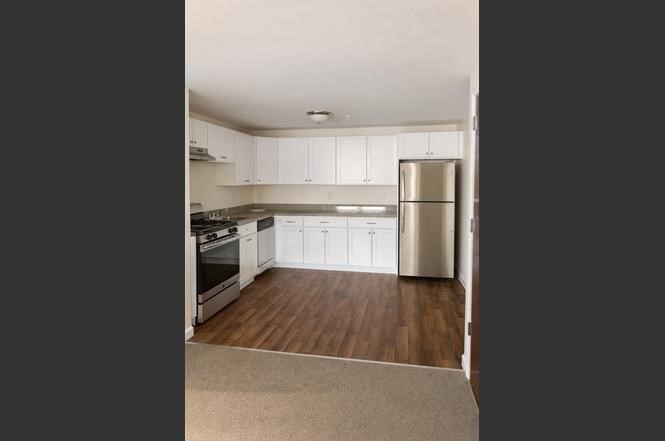 361 Hildreth Street, Unit 24 Lowell, MA 01850 - Photo 3 of 9 a kitchen with a refrigerator a stove top oven and white kitchen