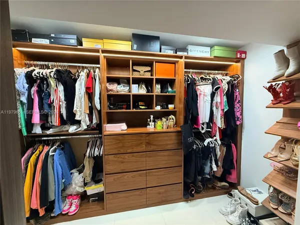 a view of walk in closet with clothes and shoes