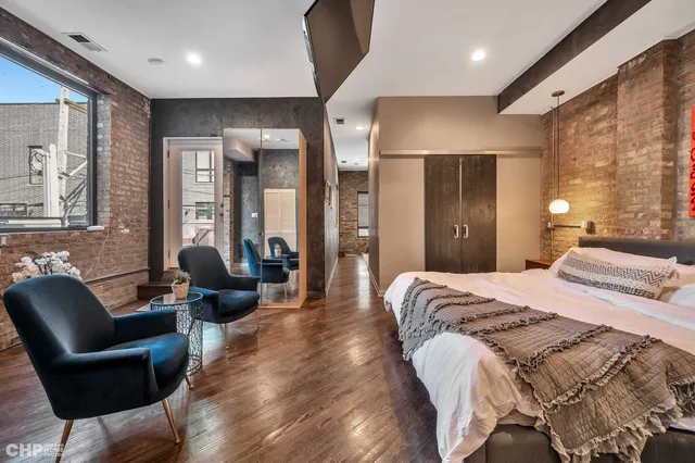 a spacious bedroom with a bed a couch and large window