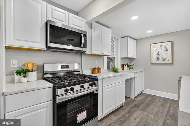 a kitchen with stainless steel appliances white cabinets and a stove top oven