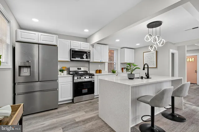 a kitchen with kitchen island a refrigerator a stove a sink and white cabinets with wooden floor