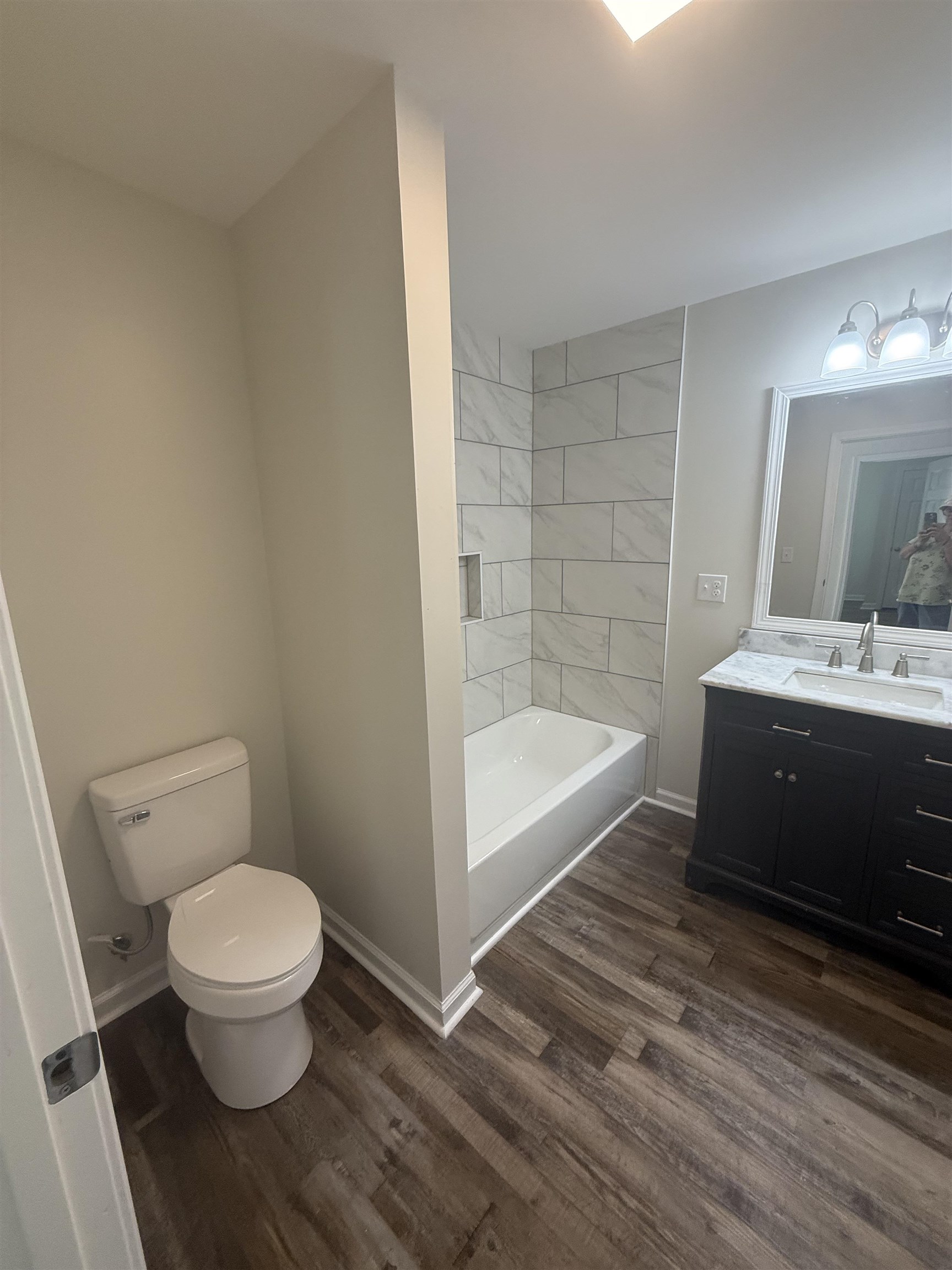 170 Leapwood Road Enville, TN 38332 - Photo 24 of 33 Bathroom featuring a tiled shower/tub combination with a recessed niche, wood-finish flooring, and a double vanity with a stone countertop