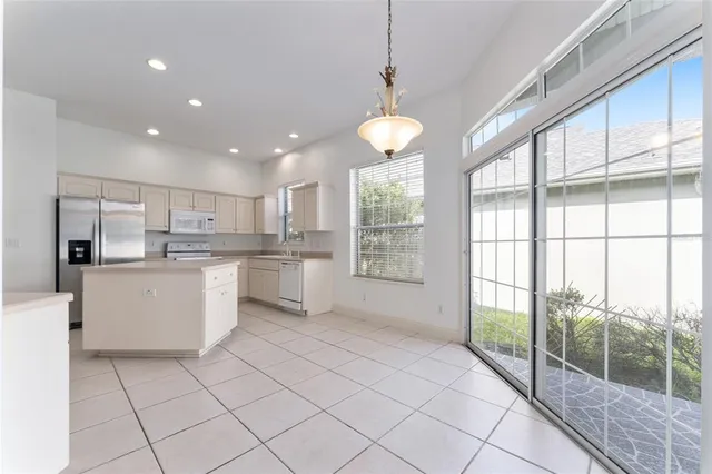 a large kitchen with kitchen island a large window cabinets a sink and stainless steel appliances