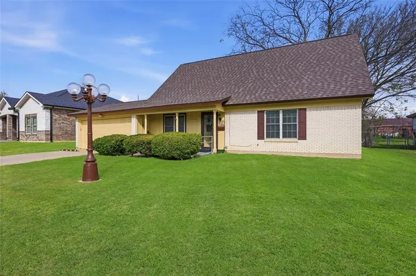 a view of a house with a yard and large trees