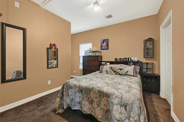a bedroom with a bed and a lamp on dresser