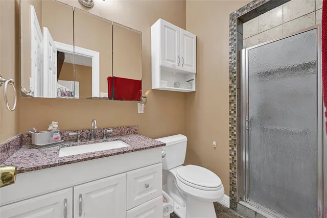 a bathroom with a granite countertop toilet sink and mirror