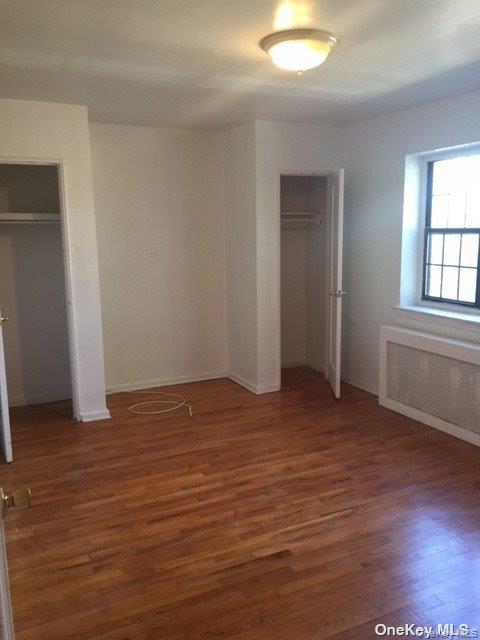 78-39 147th Street, Unit 1R Queens, NY 11367 - Photo 4 of 8 an empty room with wooden floor and windows