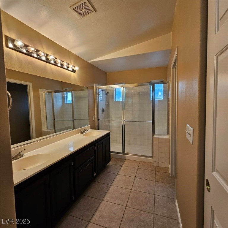1008 Venetian Hills Lane Las Vegas, NV 89144 - Photo 12 of 18 Full bathroom with light tile patterned floors, double vanity, a shower stall, and vaulted ceiling