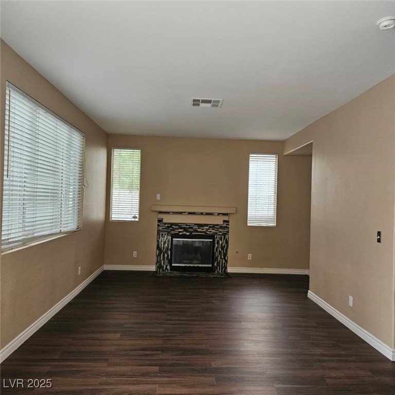 1008 Venetian Hills Lane Las Vegas, NV 89144 - Photo 7 of 18 Unfurnished living room featuring dark wood-type flooring and a fireplace with flush hearth