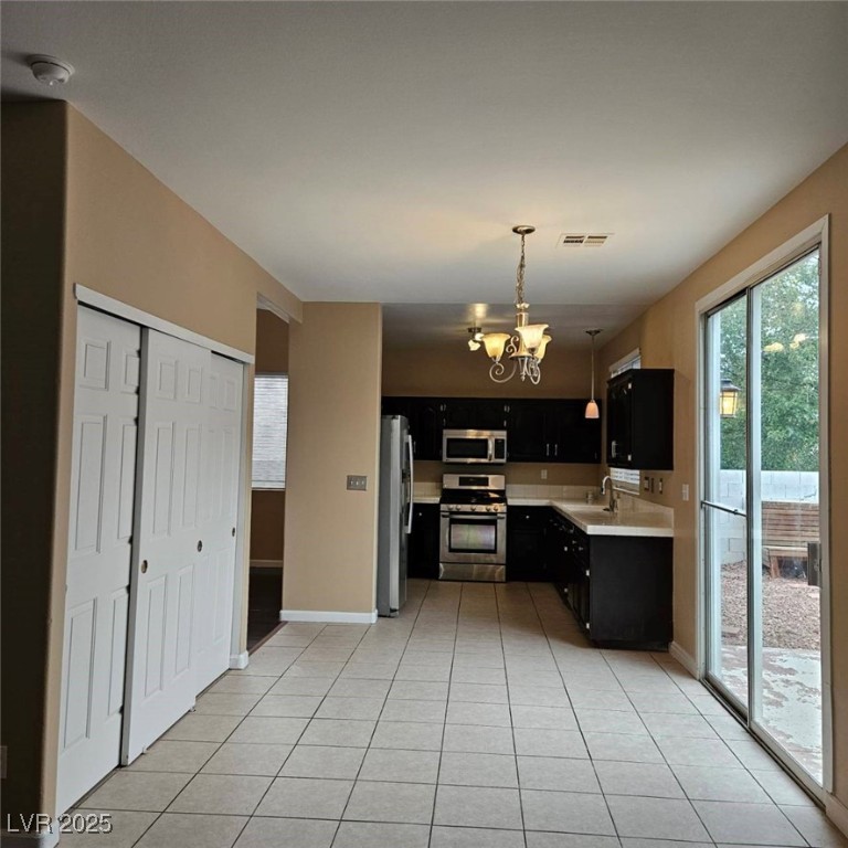 1008 Venetian Hills Lane Las Vegas, NV 89144 - Photo 8 of 18 Kitchen with dark cabinetry, a chandelier, light countertops, stainless steel appliances, and light tile patterned floors