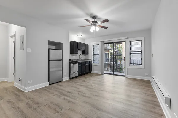a view of a kitchen with a sink cabinet an empty room and wooden floor