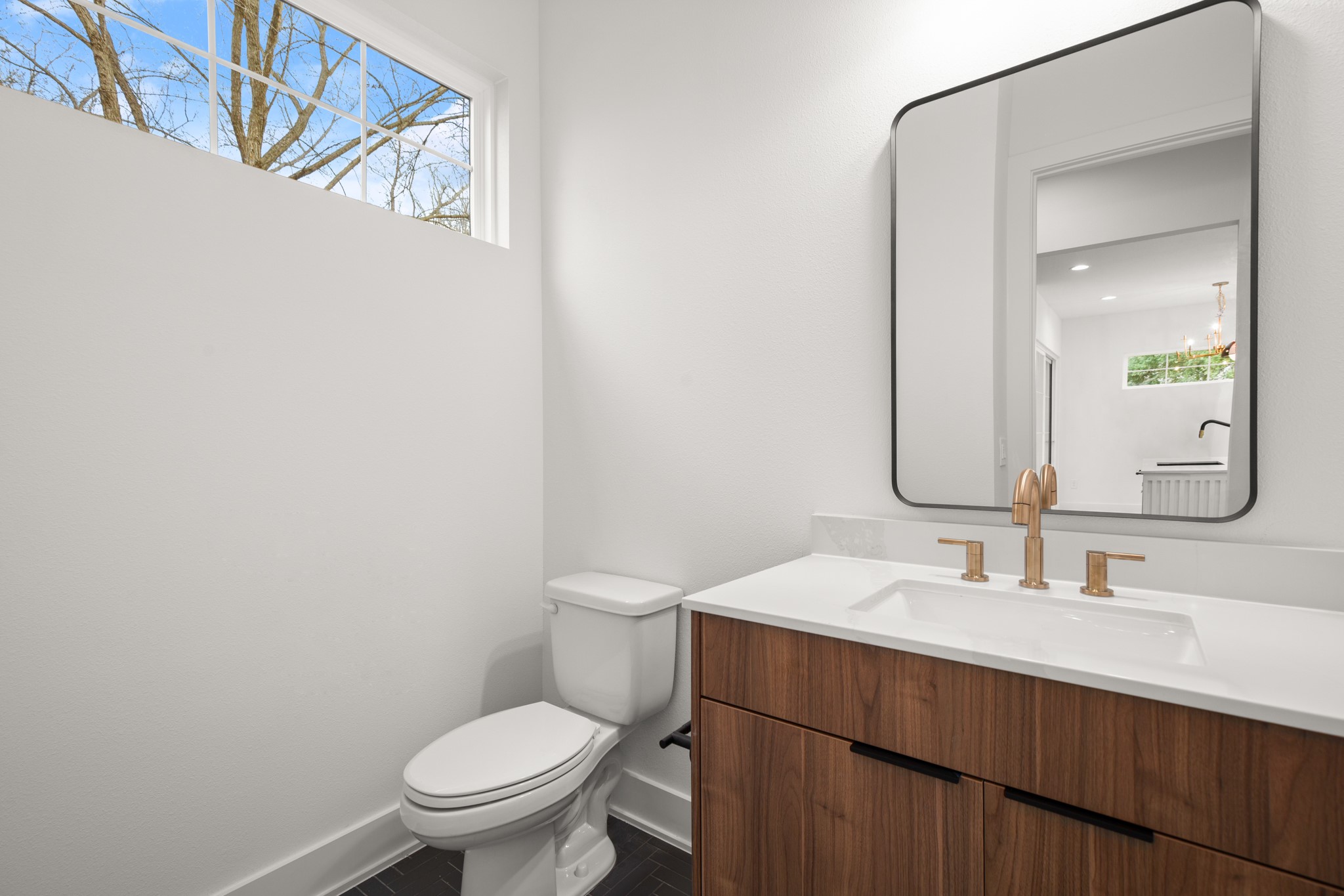601 Vermont Road, Unit 2 Austin, TX 78702 - Photo 13 of 23 Modern vanity featuring wood-finish cabinetry with black hardware, a white countertop, and an undermount sink with a brass faucet