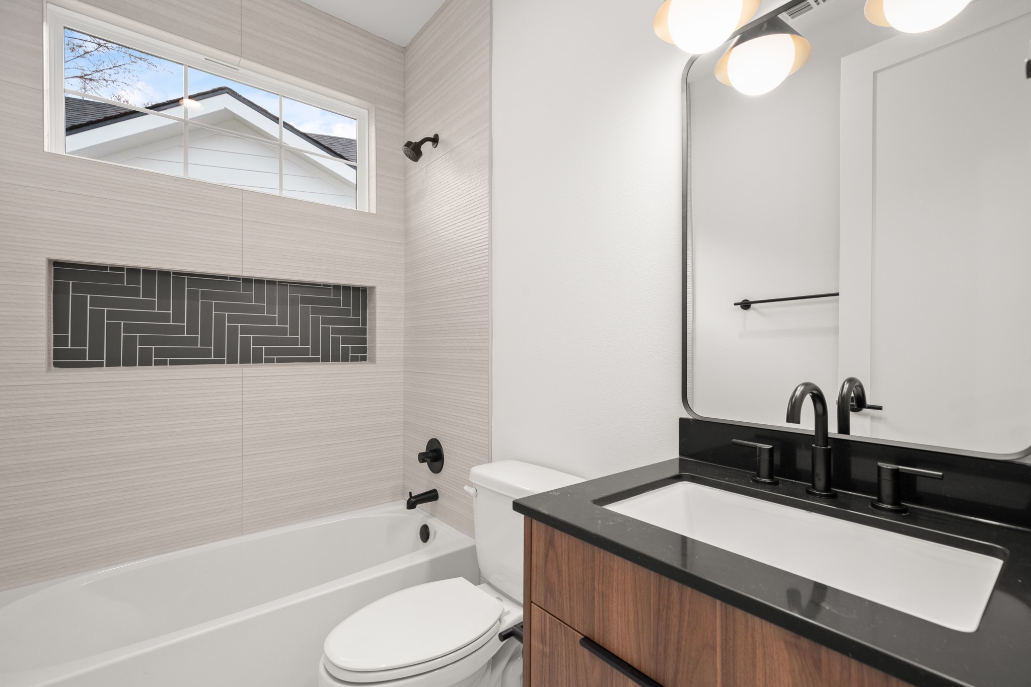 601 Vermont Road, Unit 2 Austin, TX 78702 - Photo 16 of 23 Bathroom featuring a bathtub with light-toned tiled surround, a contrasting herringbone-patterned shower niche, and a window above