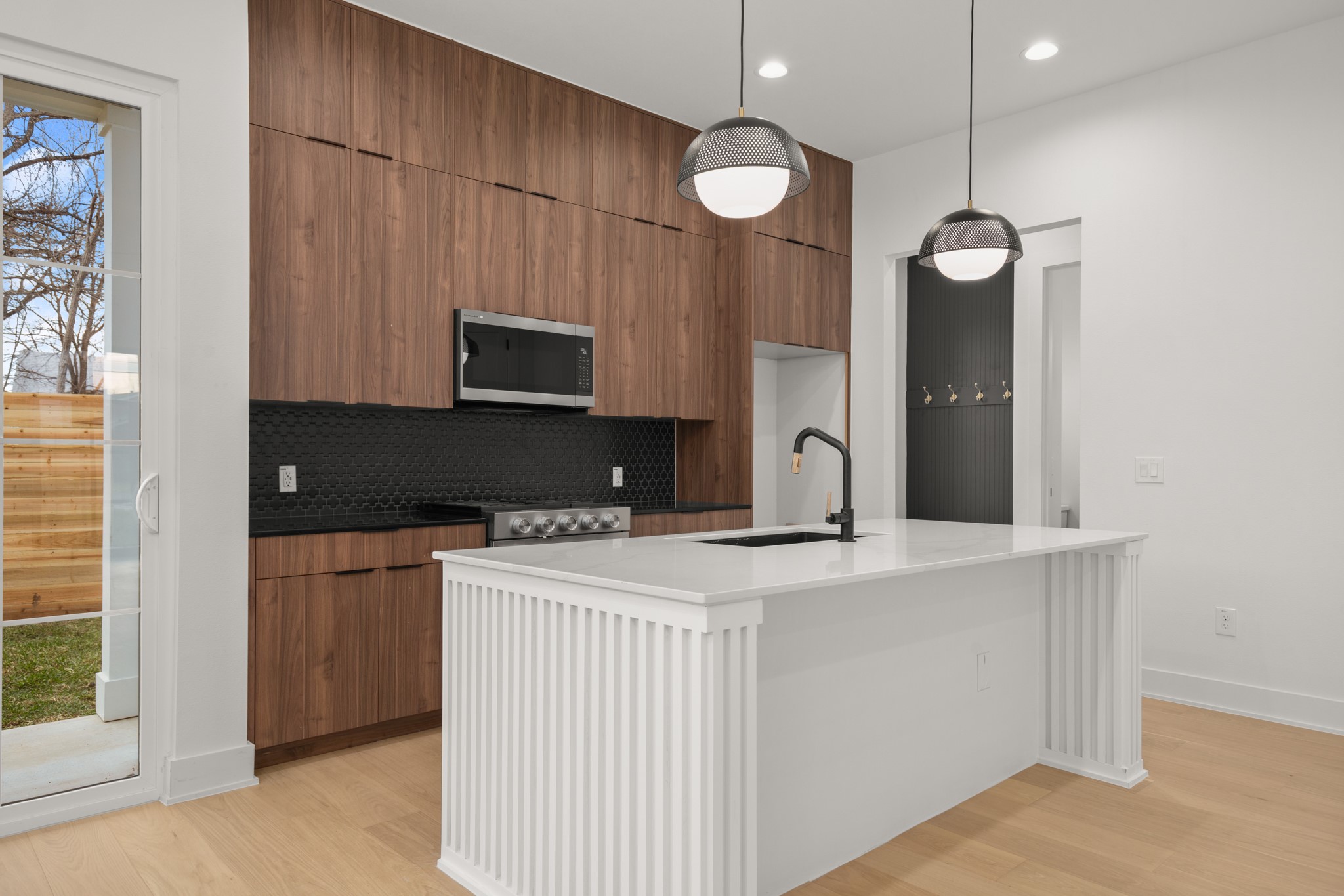 601 Vermont Road, Unit 2 Austin, TX 78702 - Photo 8 of 23 Modern kitchen featuring wood-finish cabinetry, black hexagonal tile backsplash, and stainless steel appliances