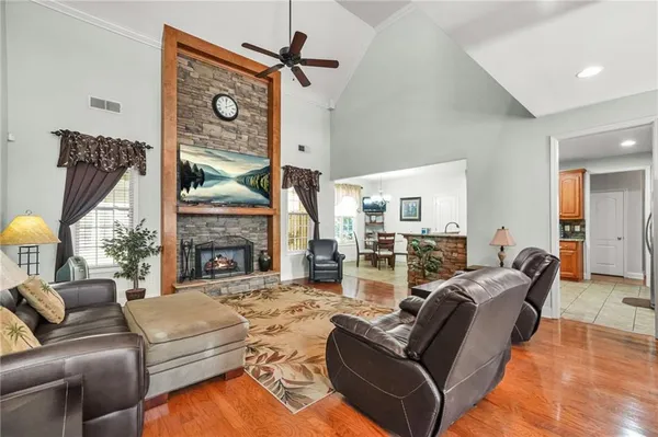 a living room with furniture a fireplace and a large mirror with wooden floor
