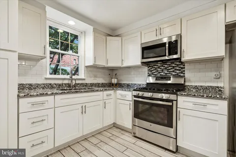 a kitchen with granite countertop white cabinets stainless steel appliances and a sink