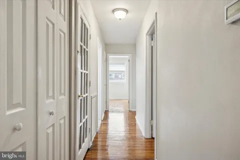 a view of a hallway with wooden floor and a bathroom