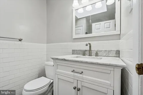 a bathroom with a granite countertop toilet sink mirror and vanity
