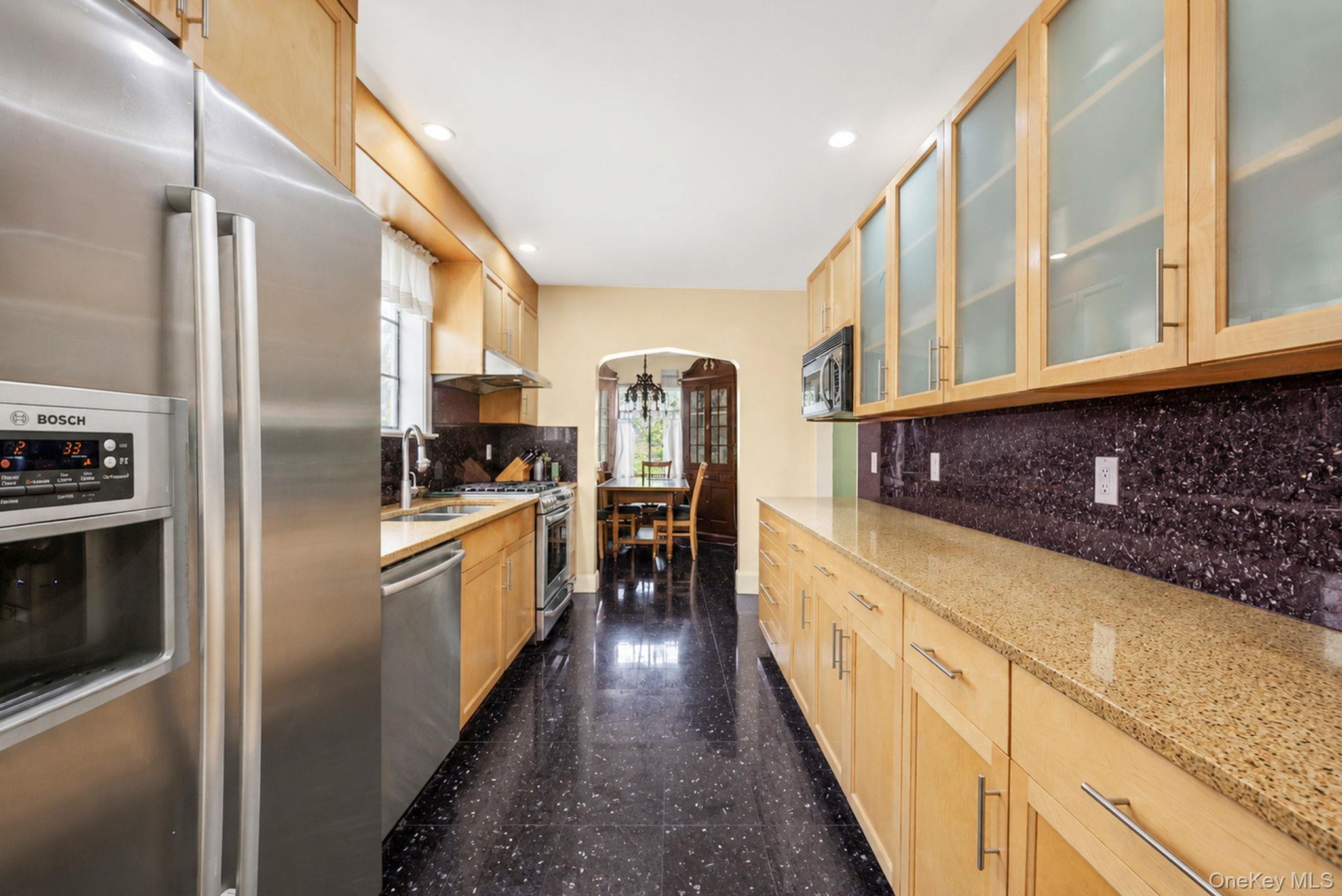 18240 Avon Road Queens, NY 11432 - Photo 12 of 30 Galley kitchen featuring stainless steel appliances, light wood-finish cabinetry, granite-style countertops, and a dark tile backsplash