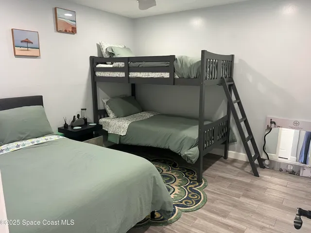 a bedroom with two beds and wooden floor