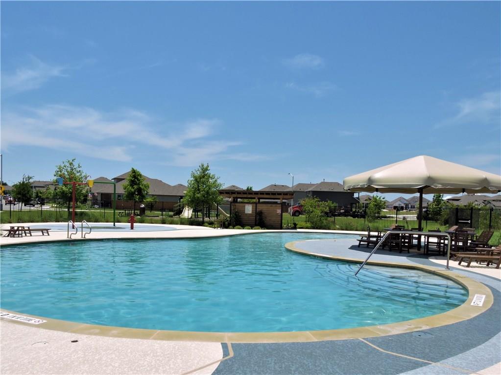 1005 Sundrops Street Leander, TX 78641 - Photo 31 of 39 a view of a swimming pool with lawn chairs under an umbrella