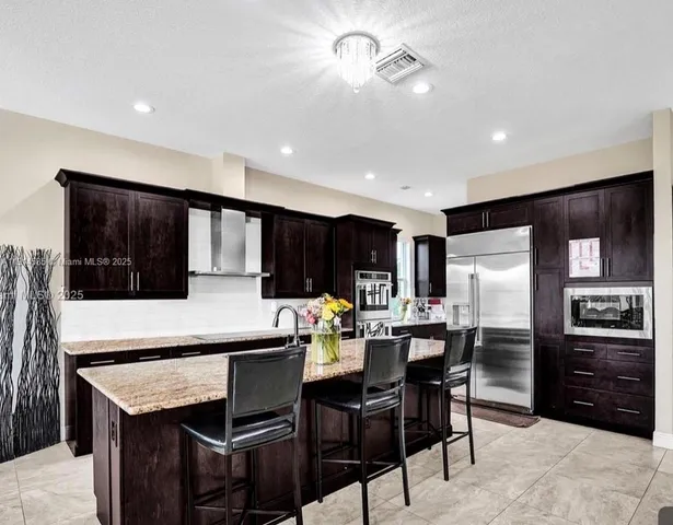 a kitchen with stainless steel appliances kitchen island granite countertop a dining table and chairs