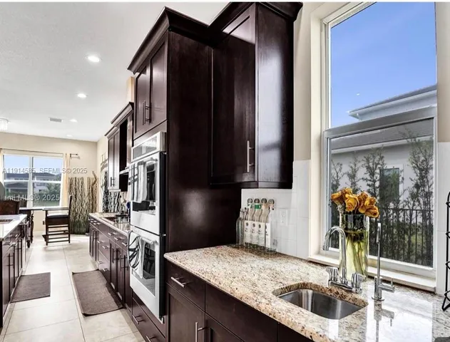 a kitchen with stainless steel appliances granite countertop a sink and a refrigerator