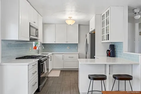 a kitchen with stainless steel appliances granite countertop a refrigerator a stove and white cabinets