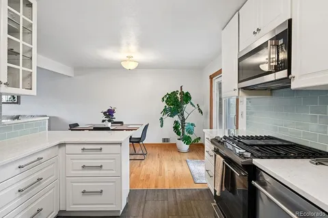 a kitchen with granite countertop stainless steel appliances a stove cabinets and wooden floor