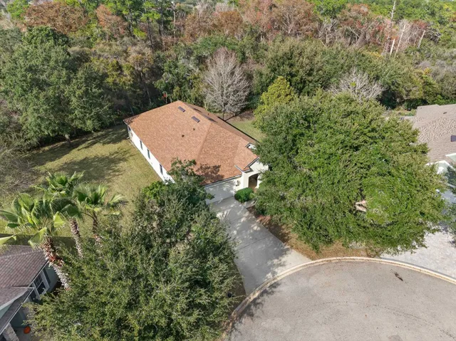 an aerial view of a house with a yard and trees all around
