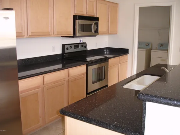 a kitchen with granite countertop a sink a stove and cabinets