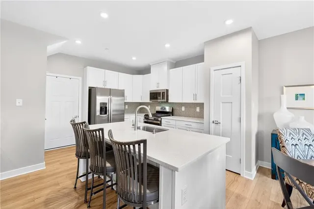 a kitchen with stainless steel appliances a table chairs refrigerator and a refrigerator