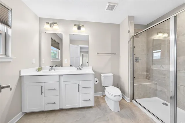 a bathroom with a double vanity sink toilet mirror and shower