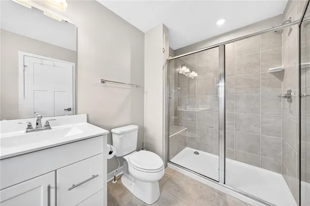 a bathroom with a shower sink vanity mirror and toilet