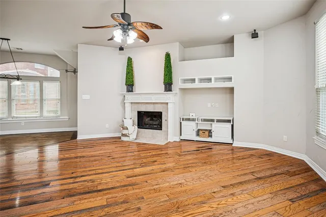 a view of empty room with wooden floor and fan