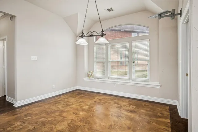 an empty room with a chandelier fan and windows
